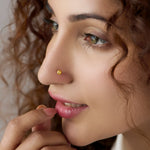 Woman wearing a minimalist 18K gold nose pin highlighting a soft everyday elegant look