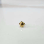 Front view of a small gold nose pin on a neutral grey background showing its compact size