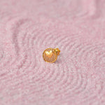 Close up of textured round heart inspired 18K gold nose pin placed on a soft pink fabric background highlighting fine surface detailing
