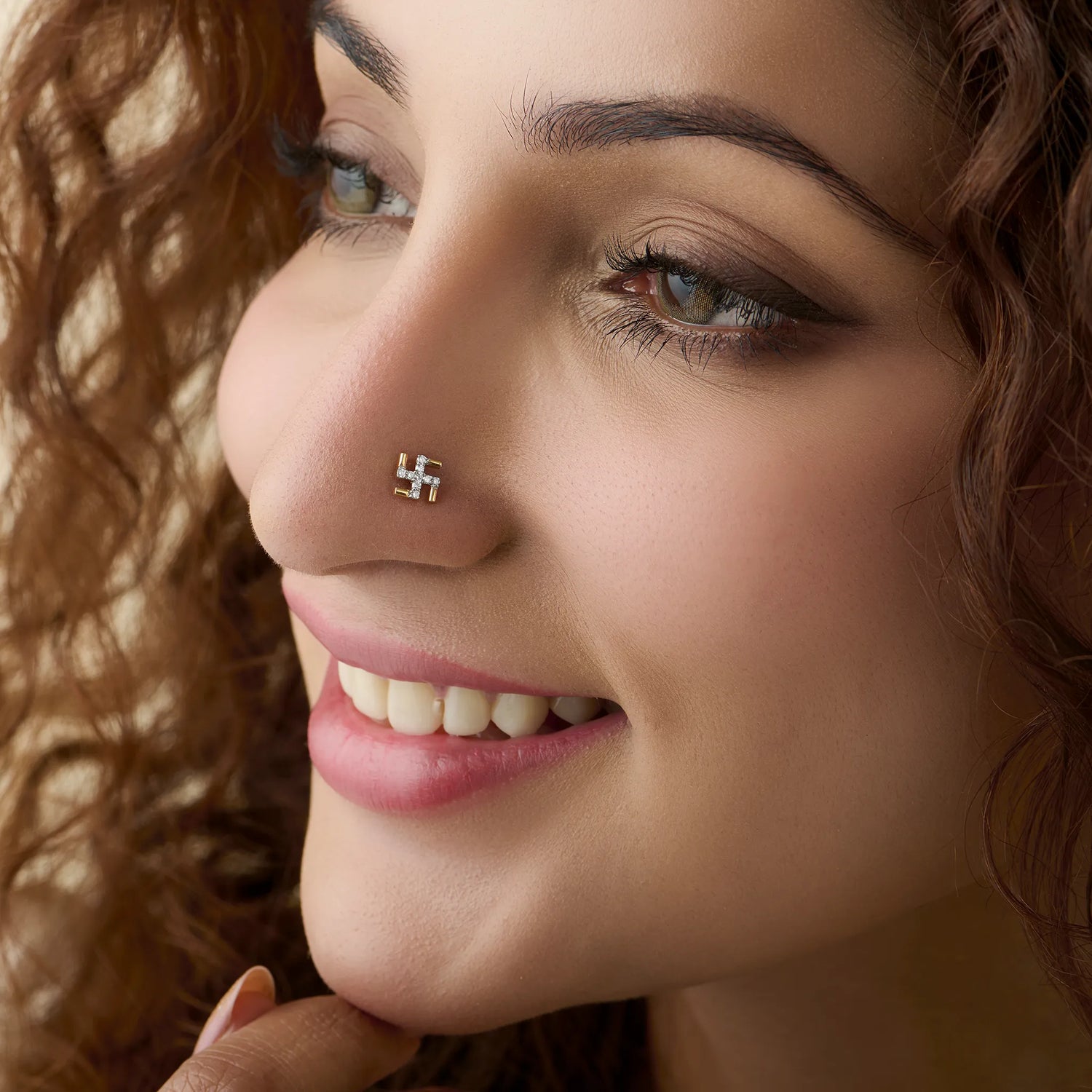 Diamond Swastik design 18K gold nose pin worn by woman.
