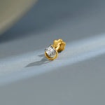 Simple gold nose pin design with round diamond on soft blue background