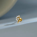 Curved floral gold nose pin design with sparkling diamonds on soft blue background