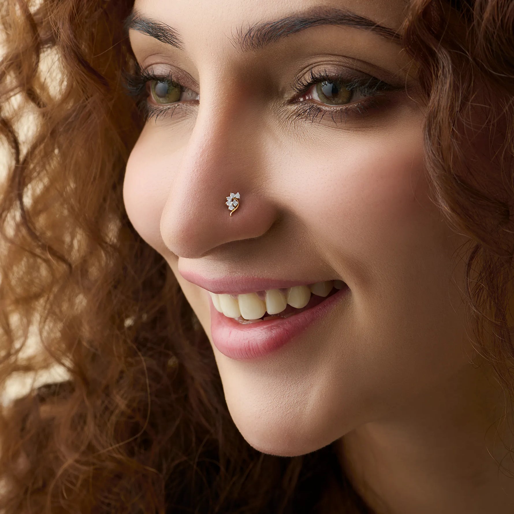 Woman wearing elegant curved gold nose pin design with diamond floral style