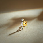 Gold nose pin with vertical row design featuring multiple sparkling stones set in a polished gold base on a soft neutral background