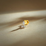 Gold nose pin with elegant curved design featuring two sparkling stones set in a polished gold base on a soft neutral background