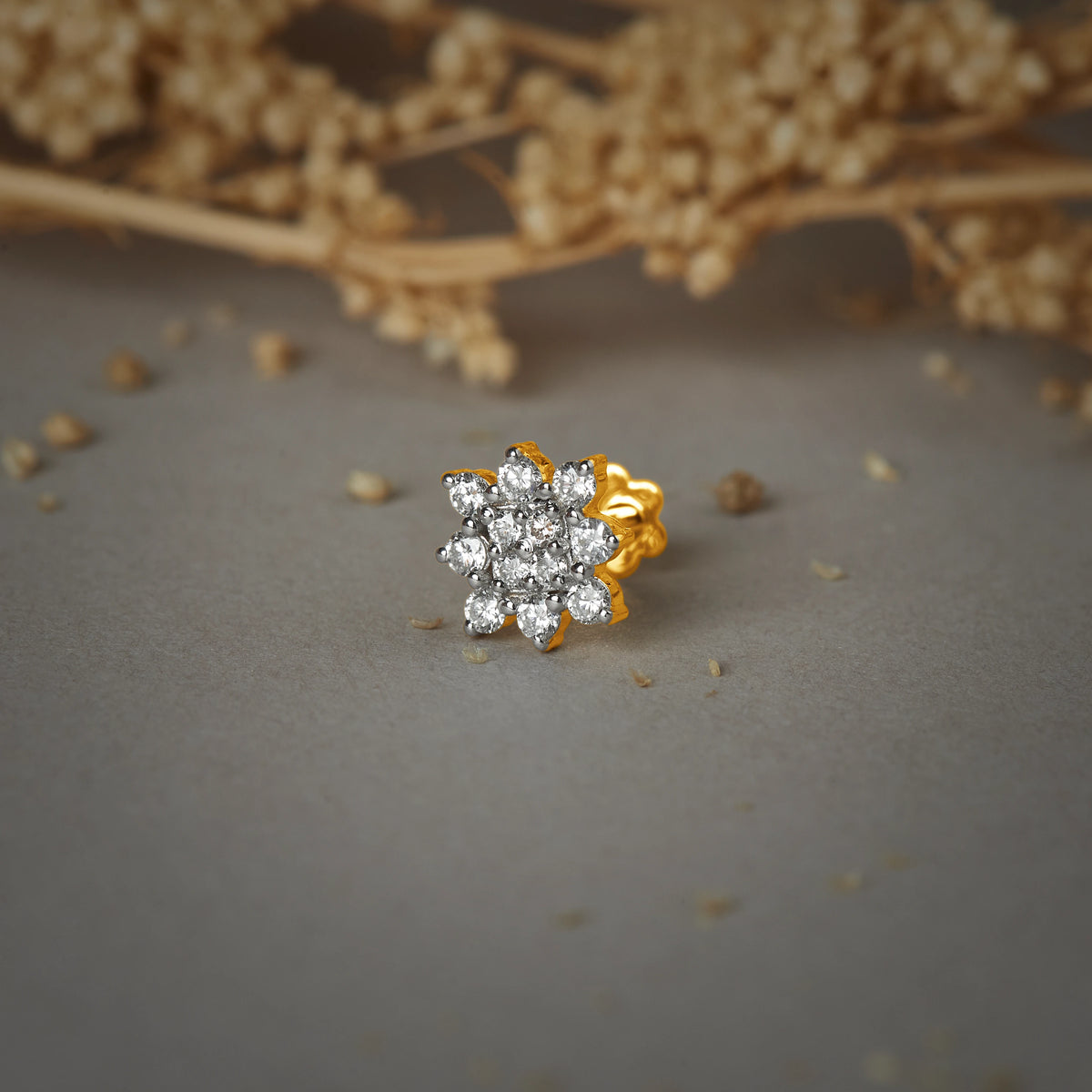 Nose pin gold with floral cluster design featuring multiple sparkling stones set in a polished gold base on a soft neutral background