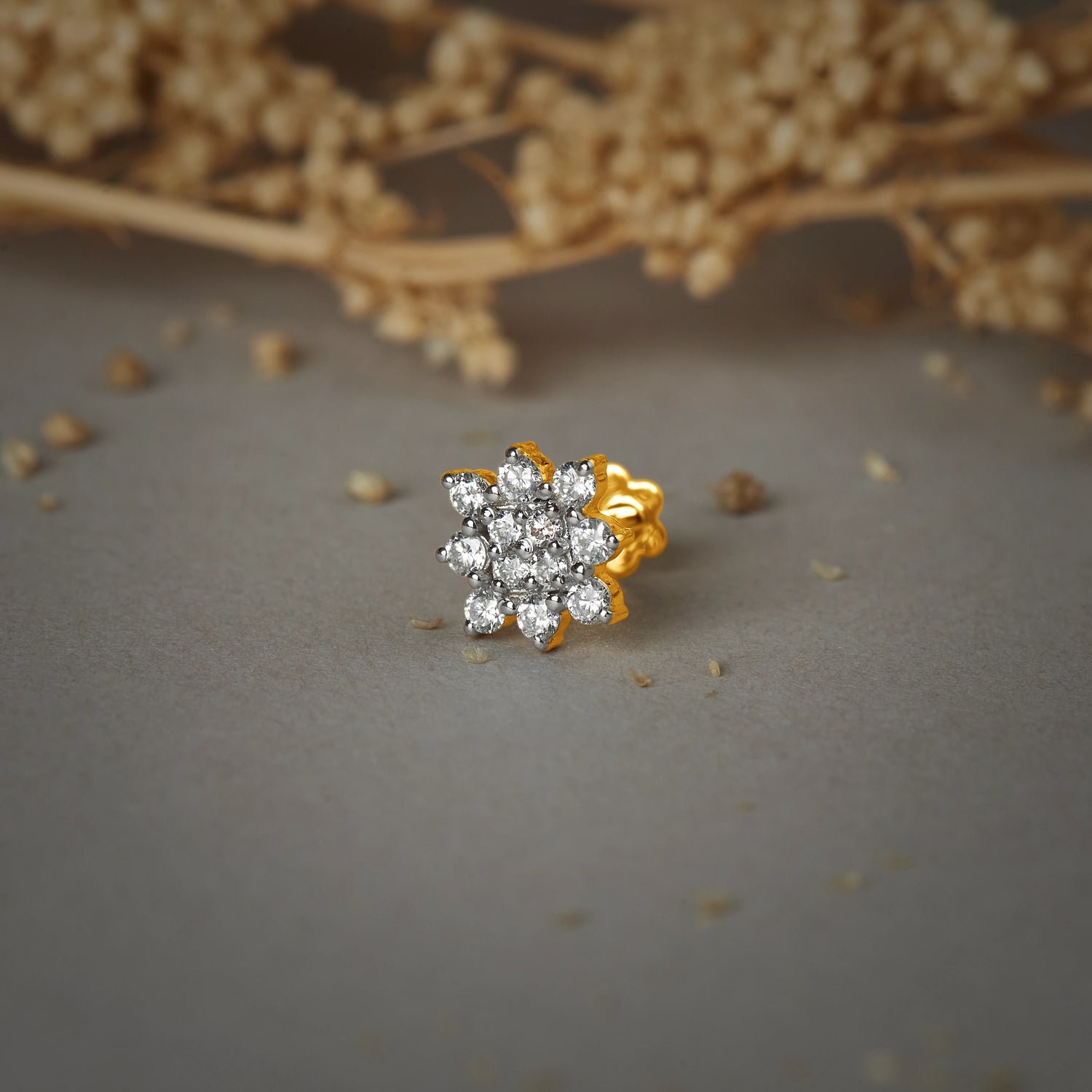 Nose pin gold with floral cluster design featuring multiple sparkling stones set in a polished gold base on a soft neutral background