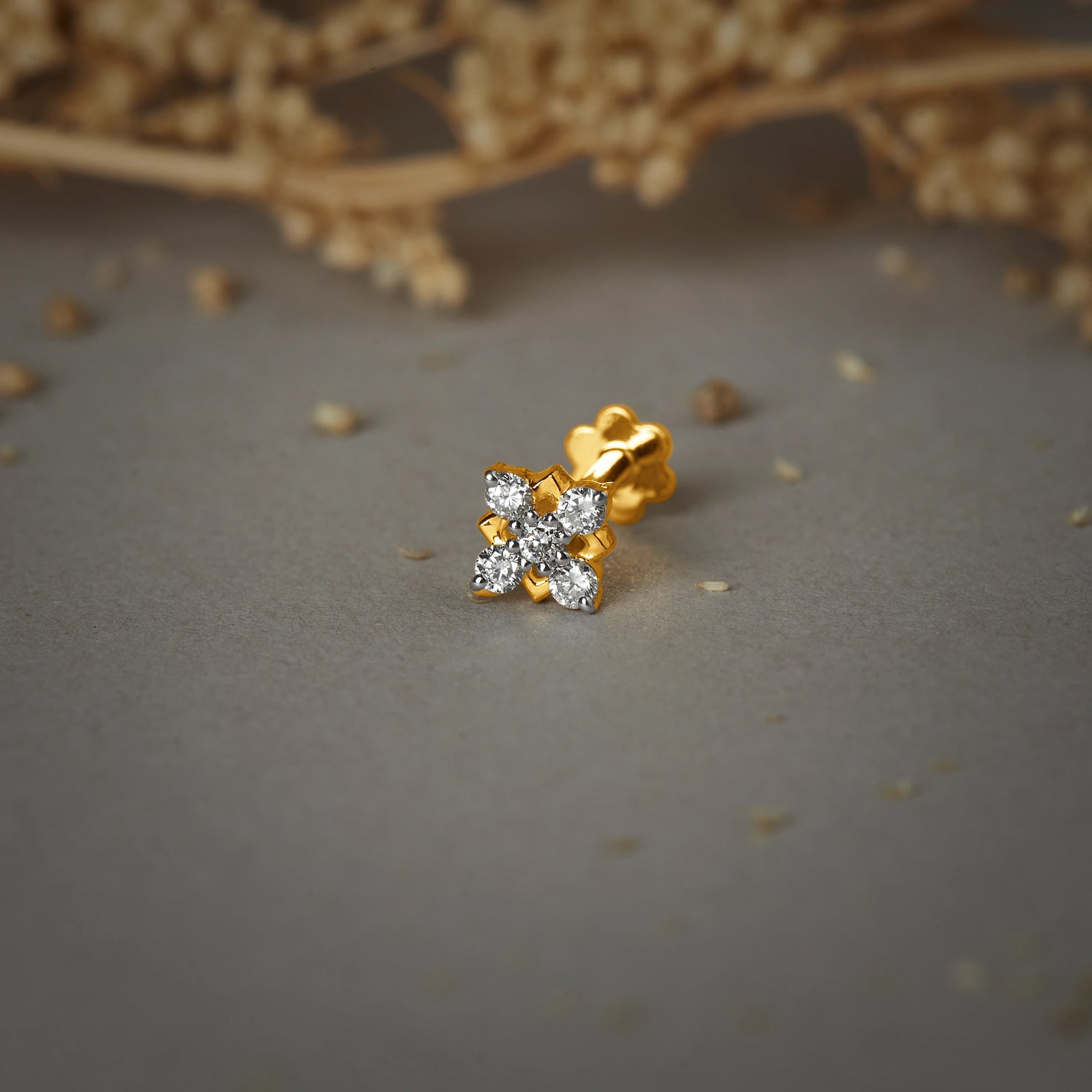 Pure gold nose pin with floral diamond design on soft neutral background, elegant women’s nose stud jewelry