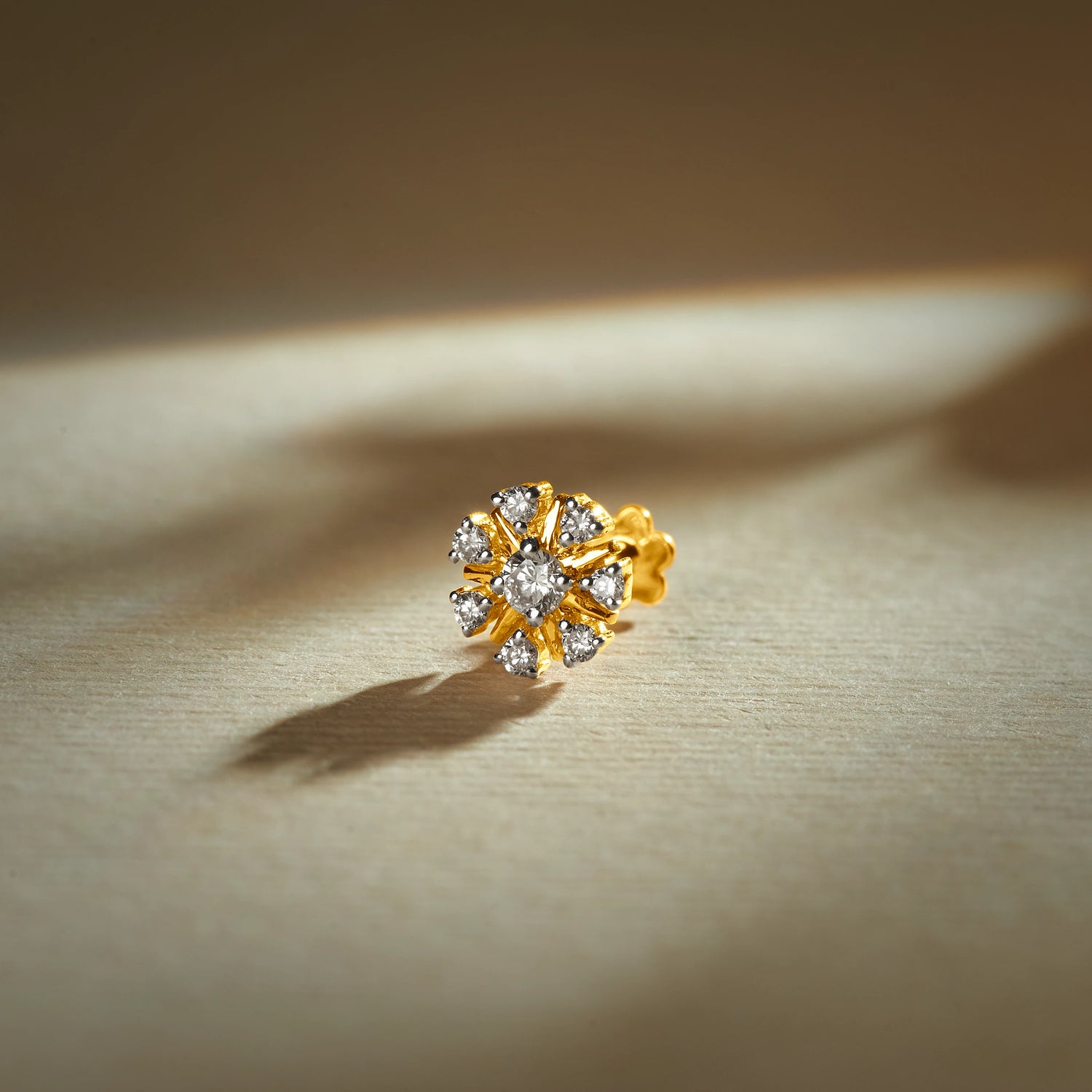 Trending nose pin gold with floral design studded with sparkling stones set in a gold base on a soft elegant background