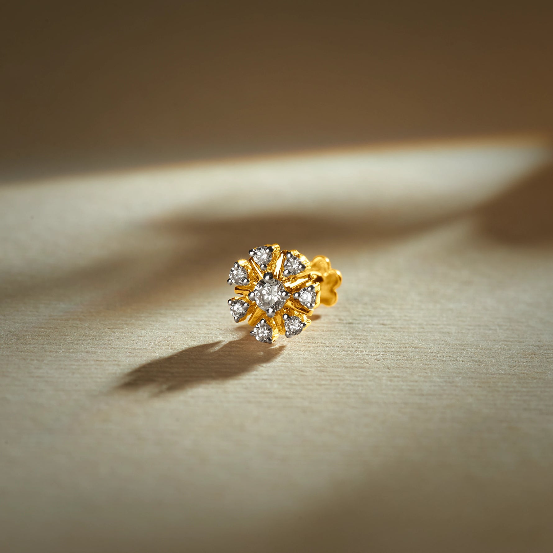 Trending nose pin gold with floral design studded with sparkling stones set in a gold base on a soft elegant background