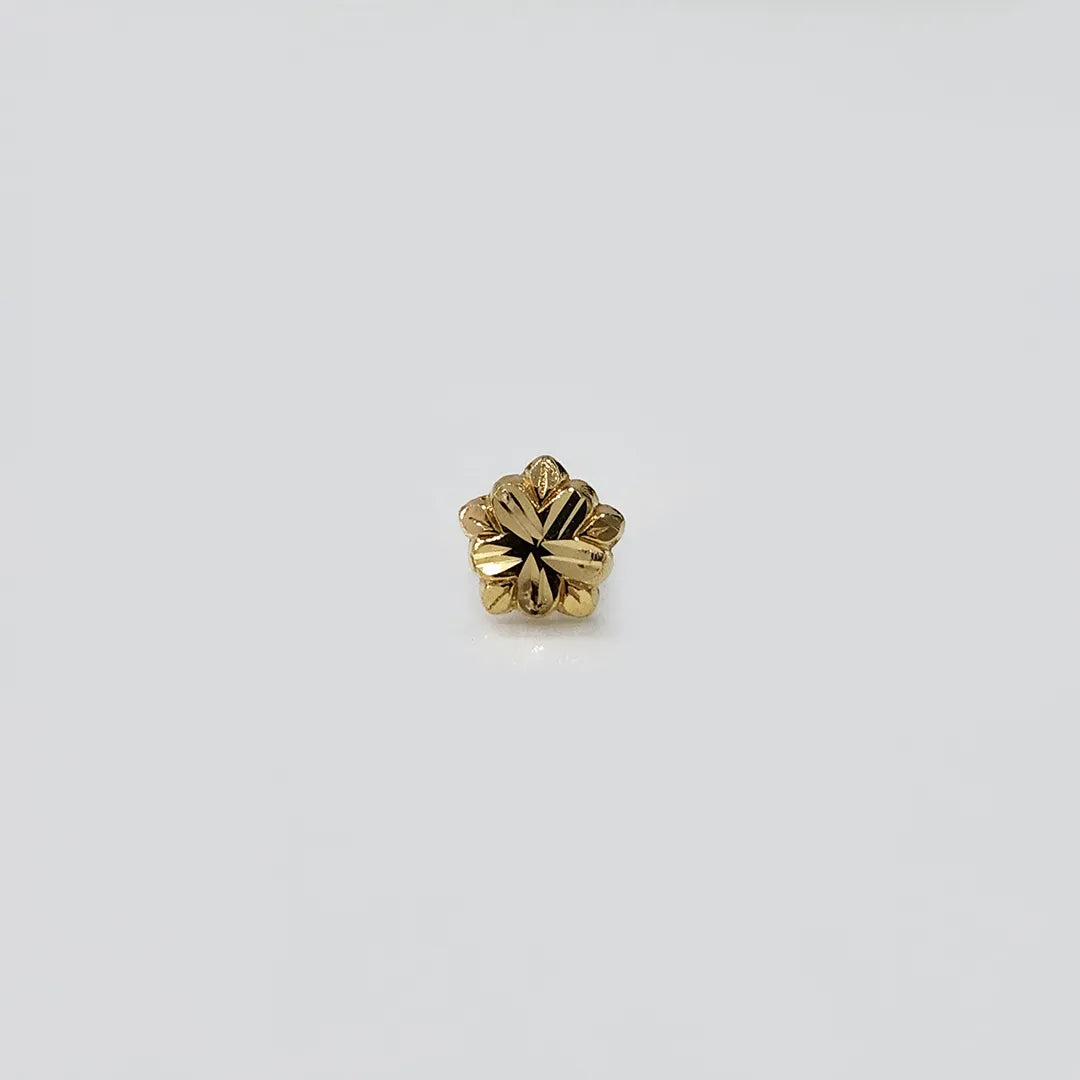 Gold flower nose pin on white surface showing detailed petal texture front view