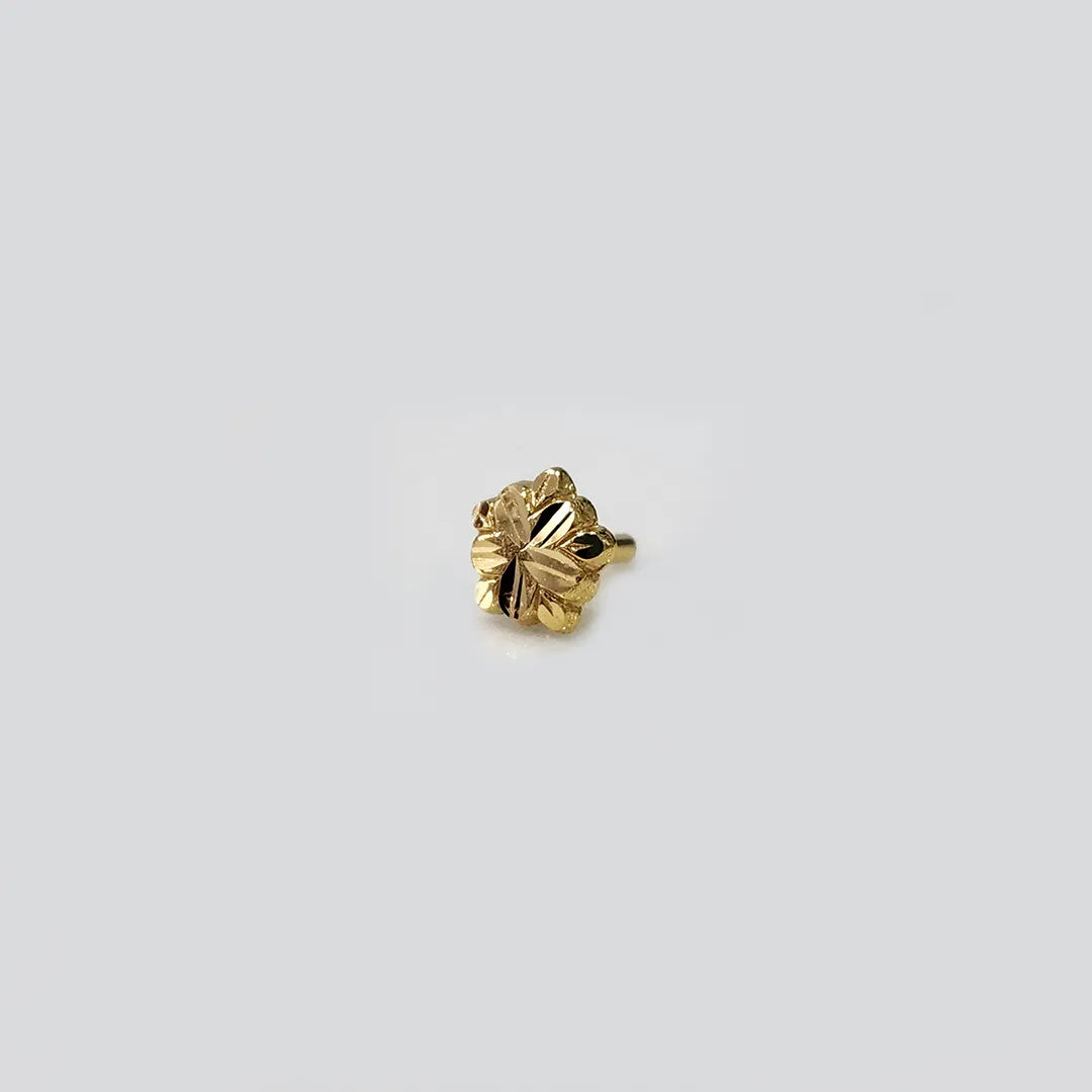 Side angle view of small floral gold nose pin placed on white surface for clarity