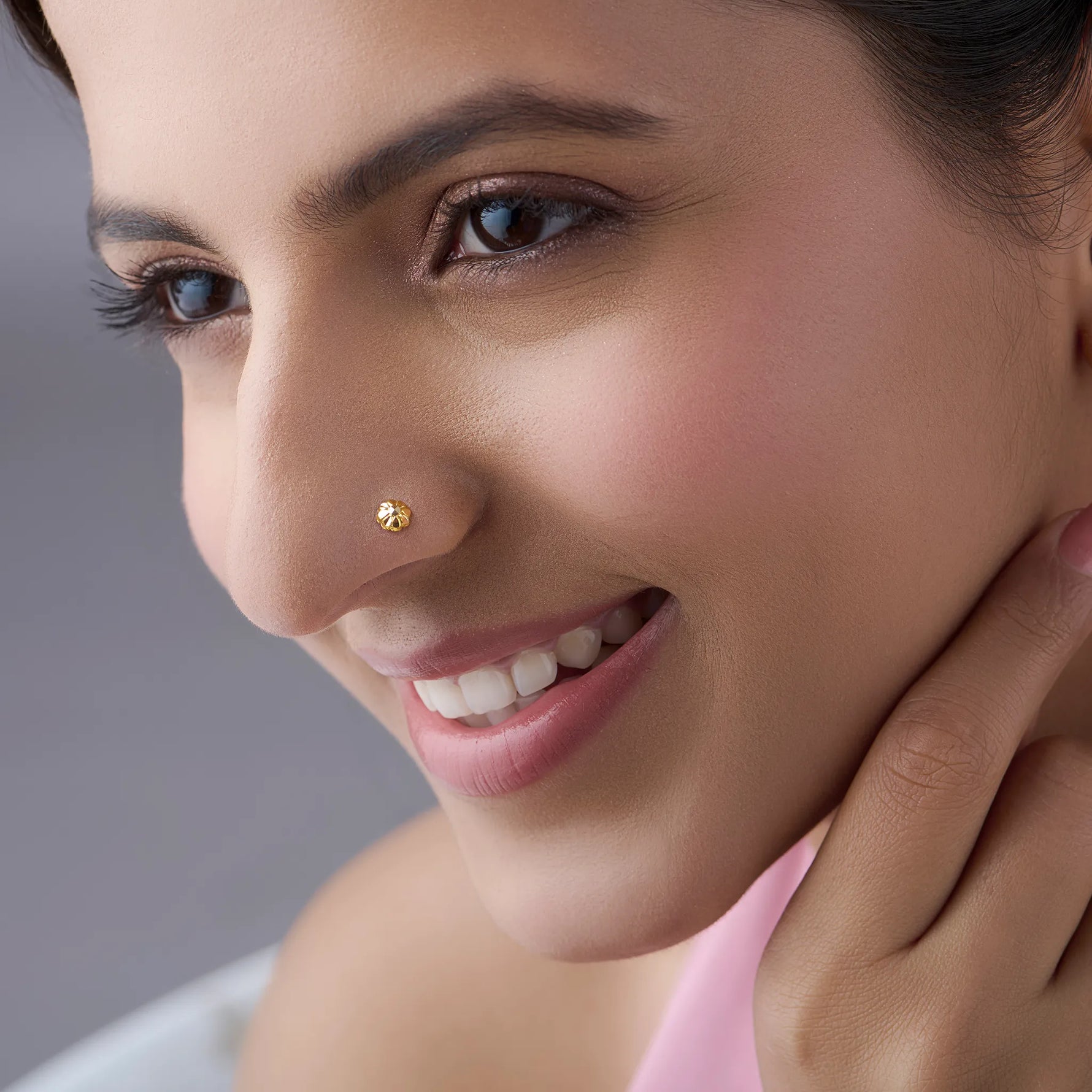 Woman wearing a minimal gold nose pin showcasing a soft everyday look with a gentle smile