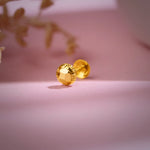 Gold textured 18K nose pin gold placed on a soft pink background highlighting its shine