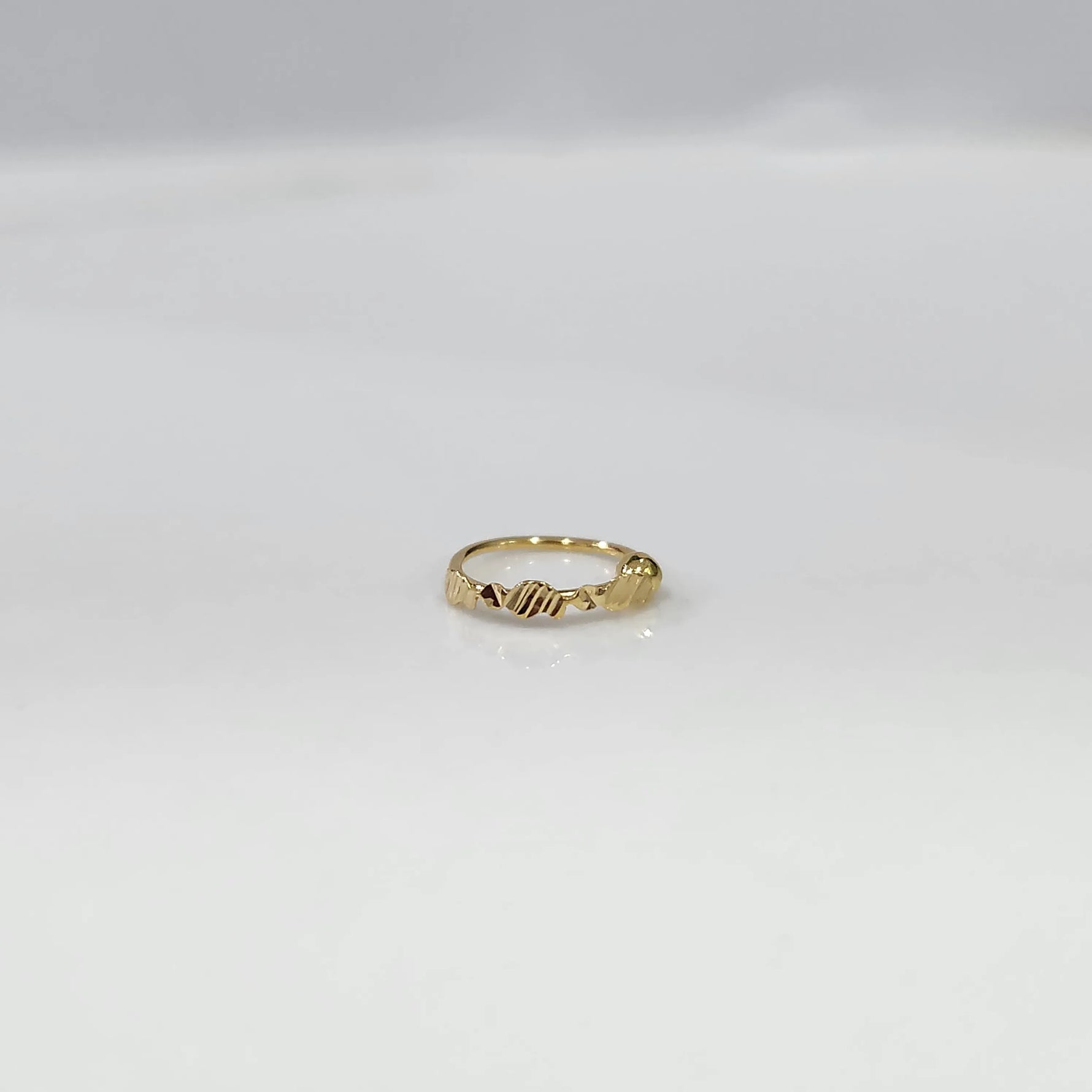 Front view of a petite 18K gold nose ring placed on a clean white surface showing fine detailing