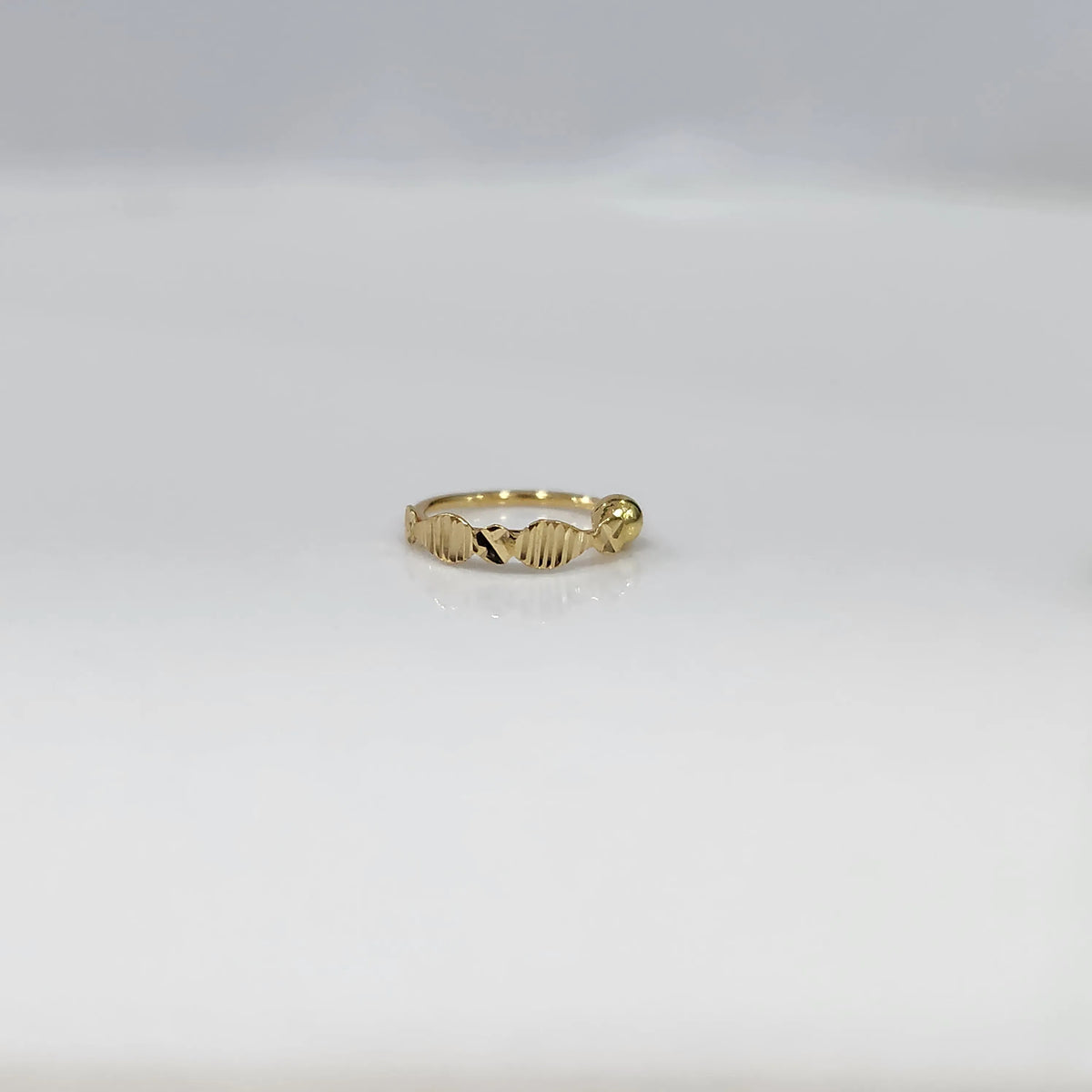 Front view of slim zigzag design 18K gold nose ring placed flat on a white background highlighting its delicate detailing