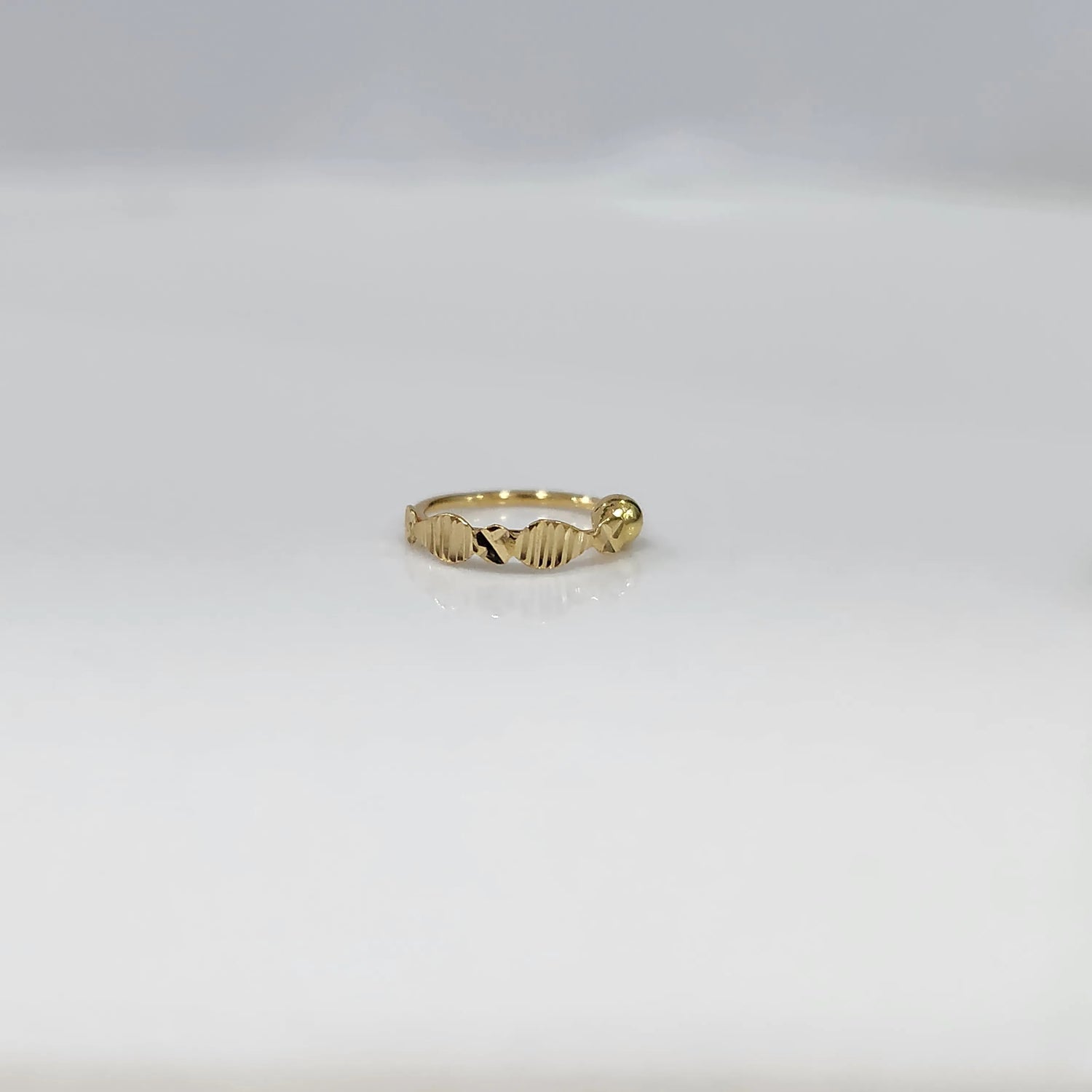 Front view of slim zigzag design 18K gold nose ring placed flat on a white background highlighting its delicate detailing