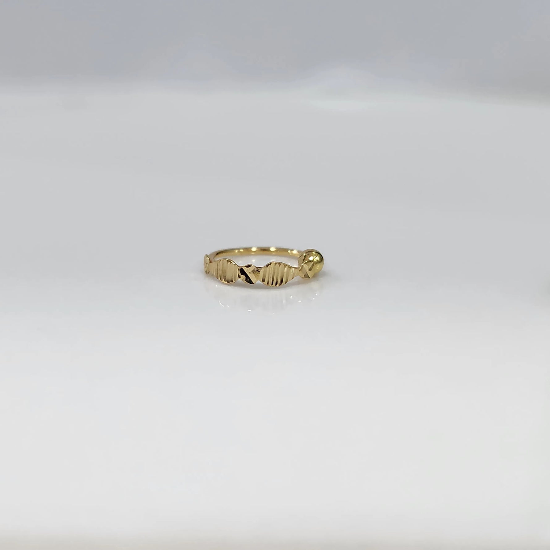 Front view of slim zigzag design 18K gold nose ring placed flat on a white background highlighting its delicate detailing
