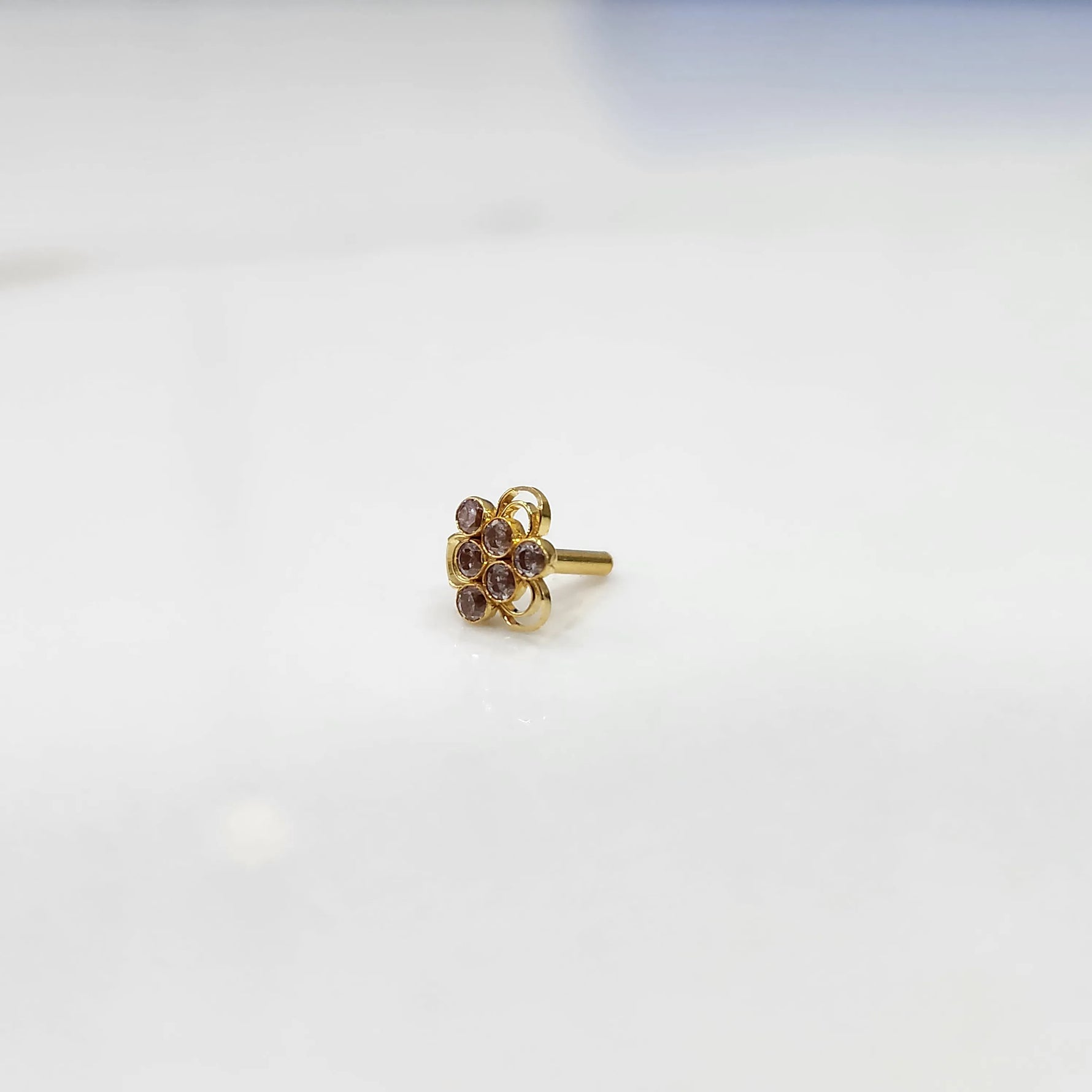Slight angled view of the stone nose pin on a white surface emphasizing the raised stone arrangement