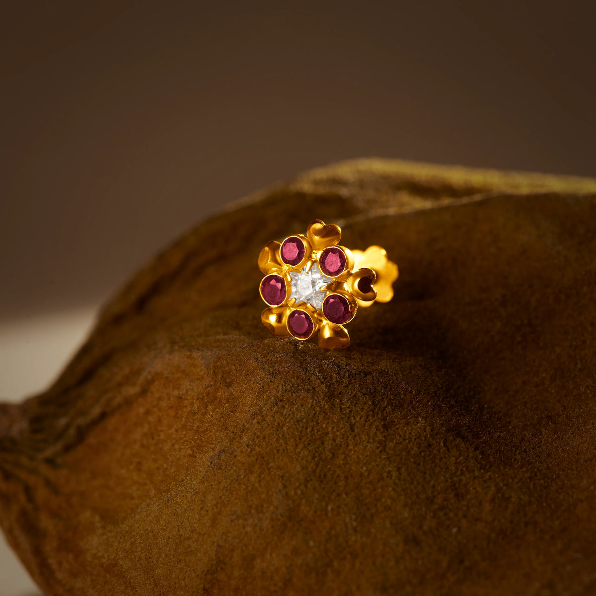 Stone Nose Pin Gold gemstones on a brown textured surface