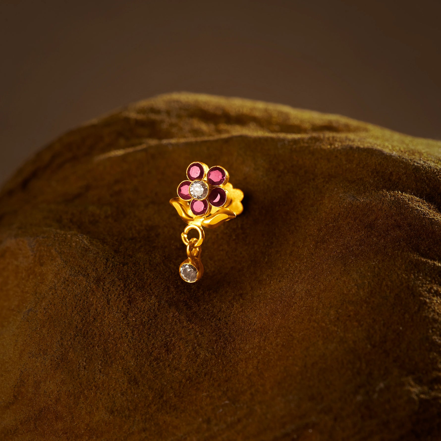 Flower Delite 18K crimson stone gold nose pin with floral drop design on textured background