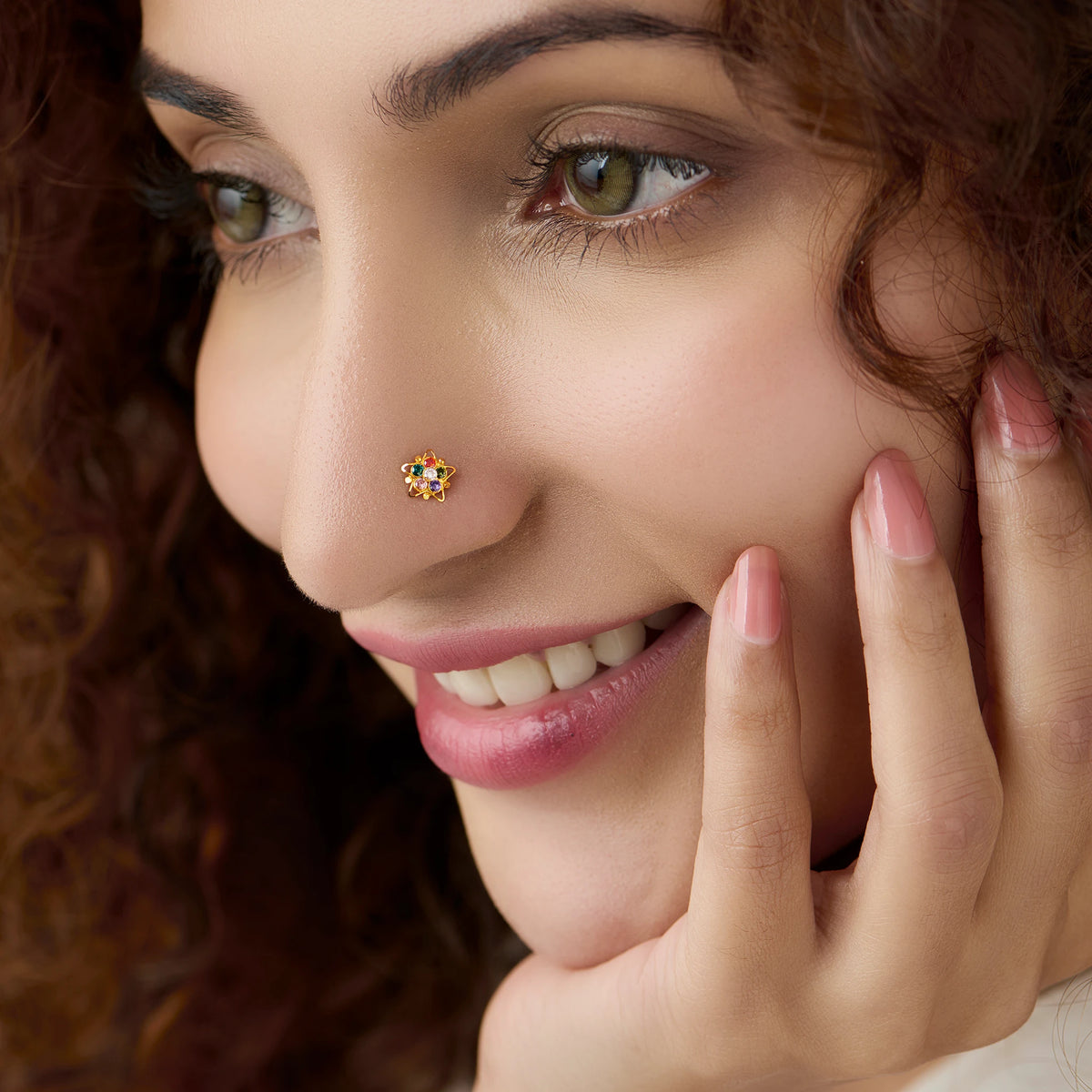 Woman wearing nose pin design gold with small floral gemstone cluster