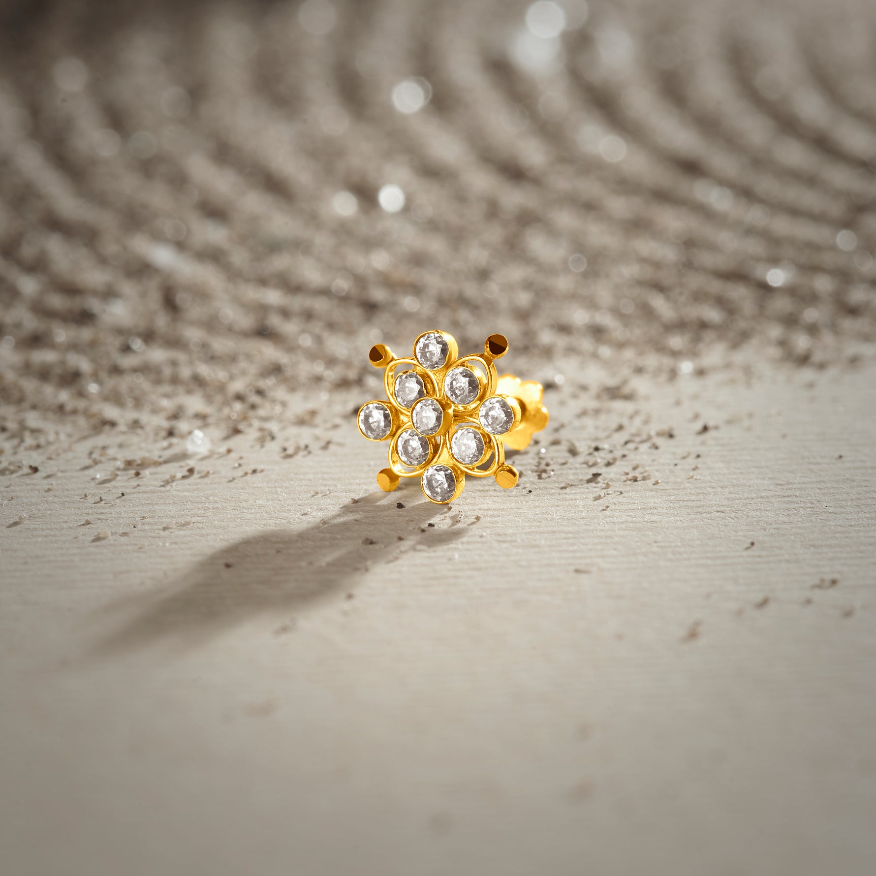 Stone gold nose pin with floral cluster design on textured neutral background