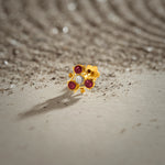 Tiny nose pin gold floral stones on textured surface