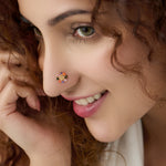 Woman wearing gold nose pin design with multicolor floral pattern close up