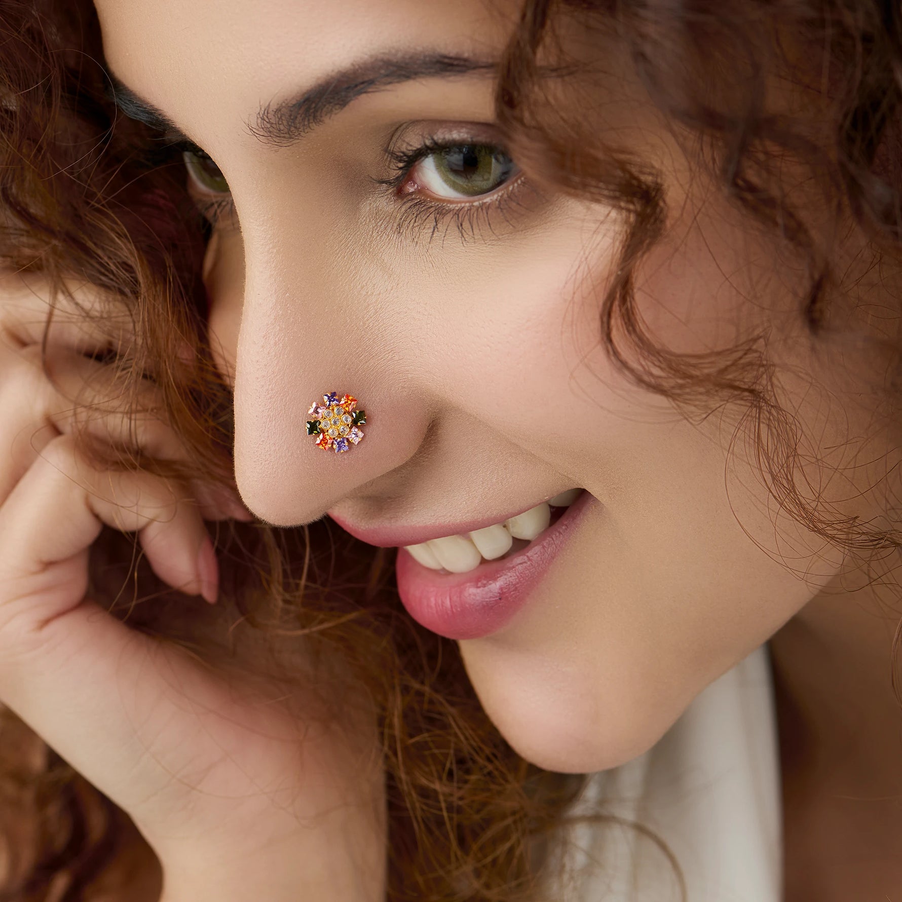 Woman wearing gold nose pin design with multicolor floral pattern close up