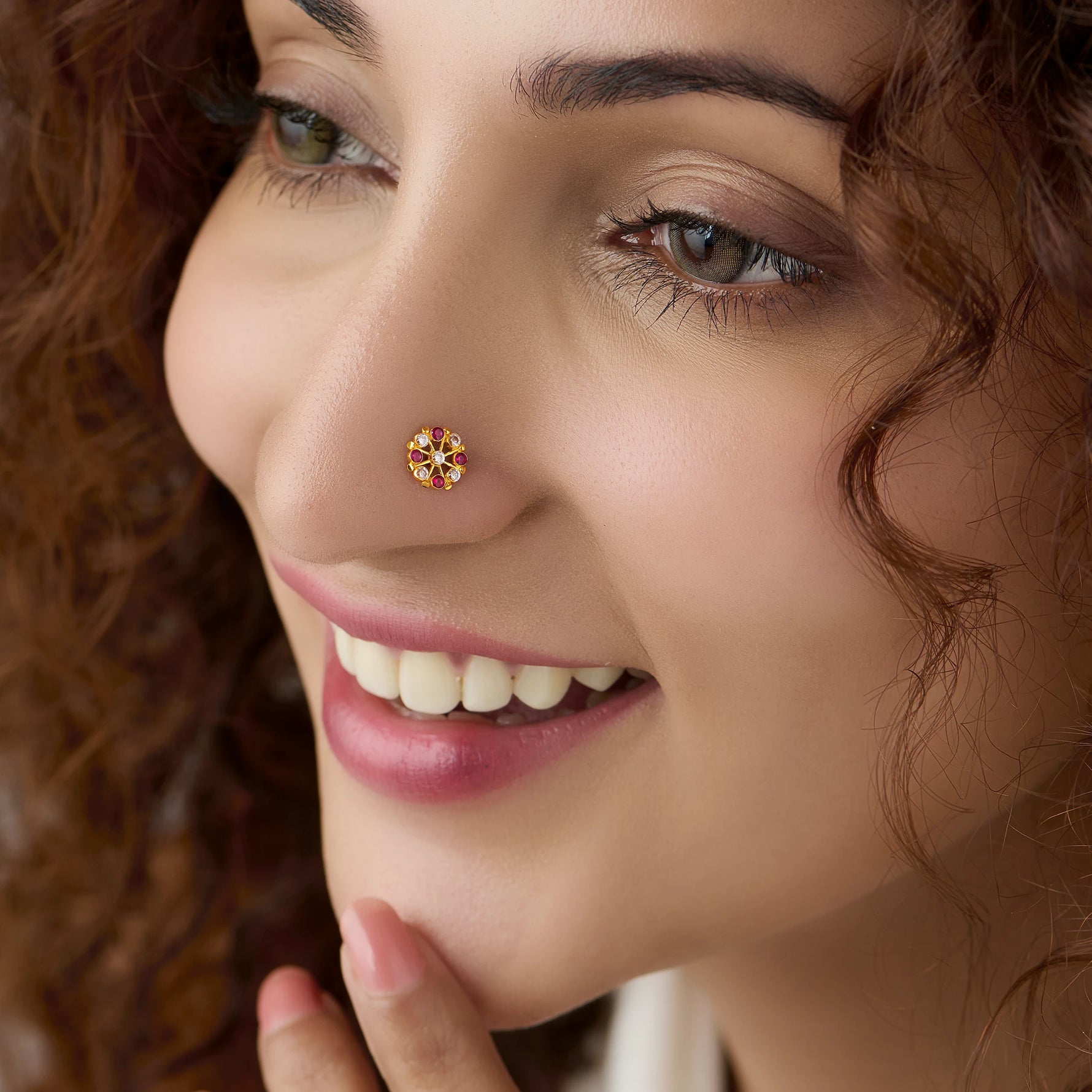 Woman wearing gold pin nose with floral diamond design close up