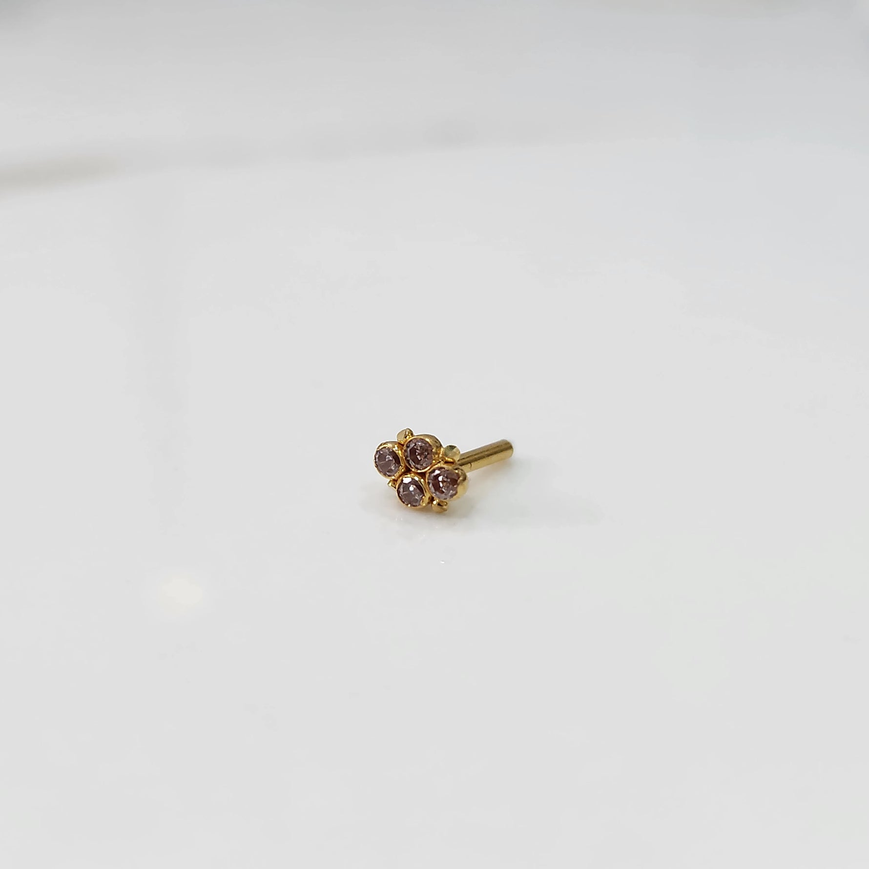 Women's gold nose pin design side view with small gemstone floral design