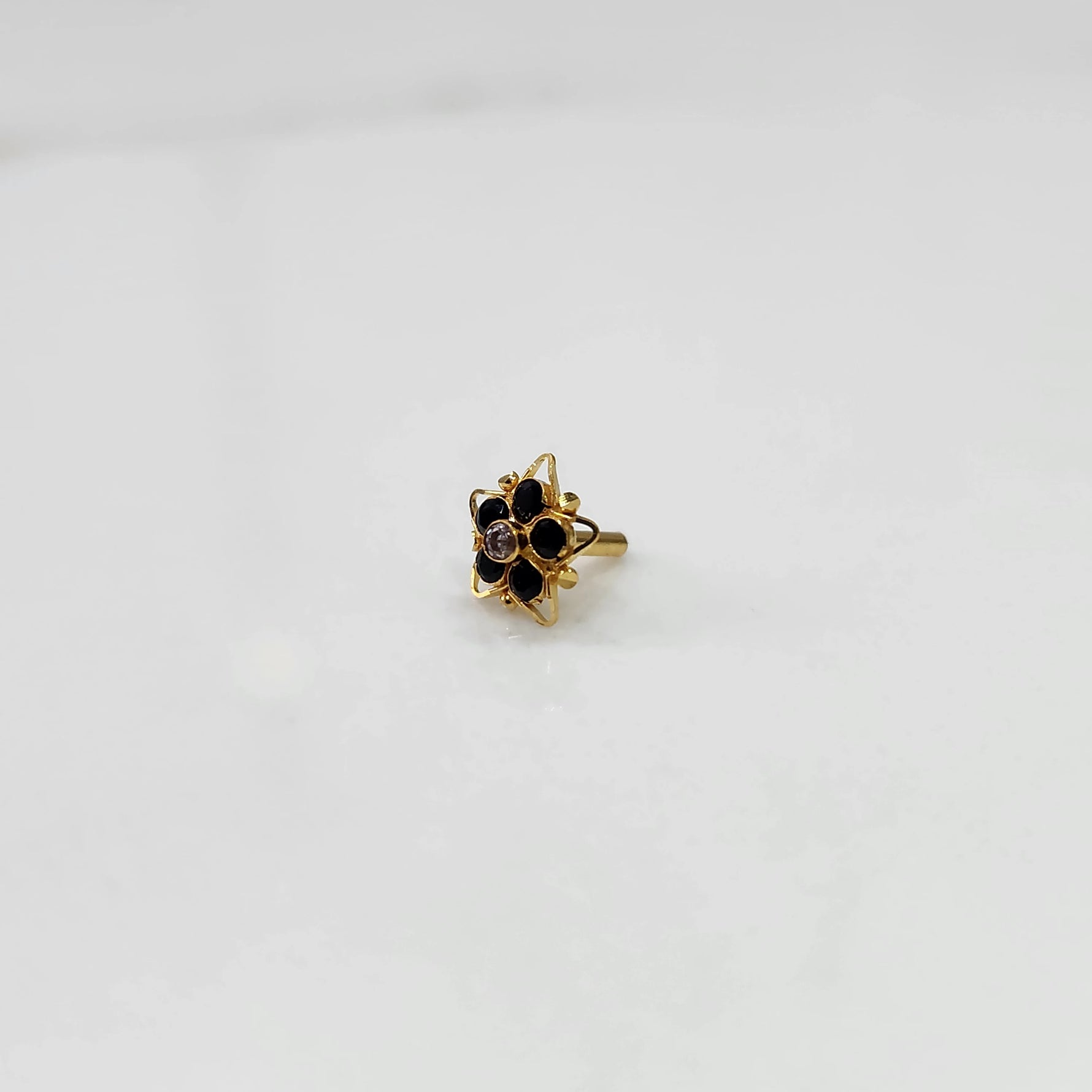 Side view nose pin design gold with black stone floral pattern on white background