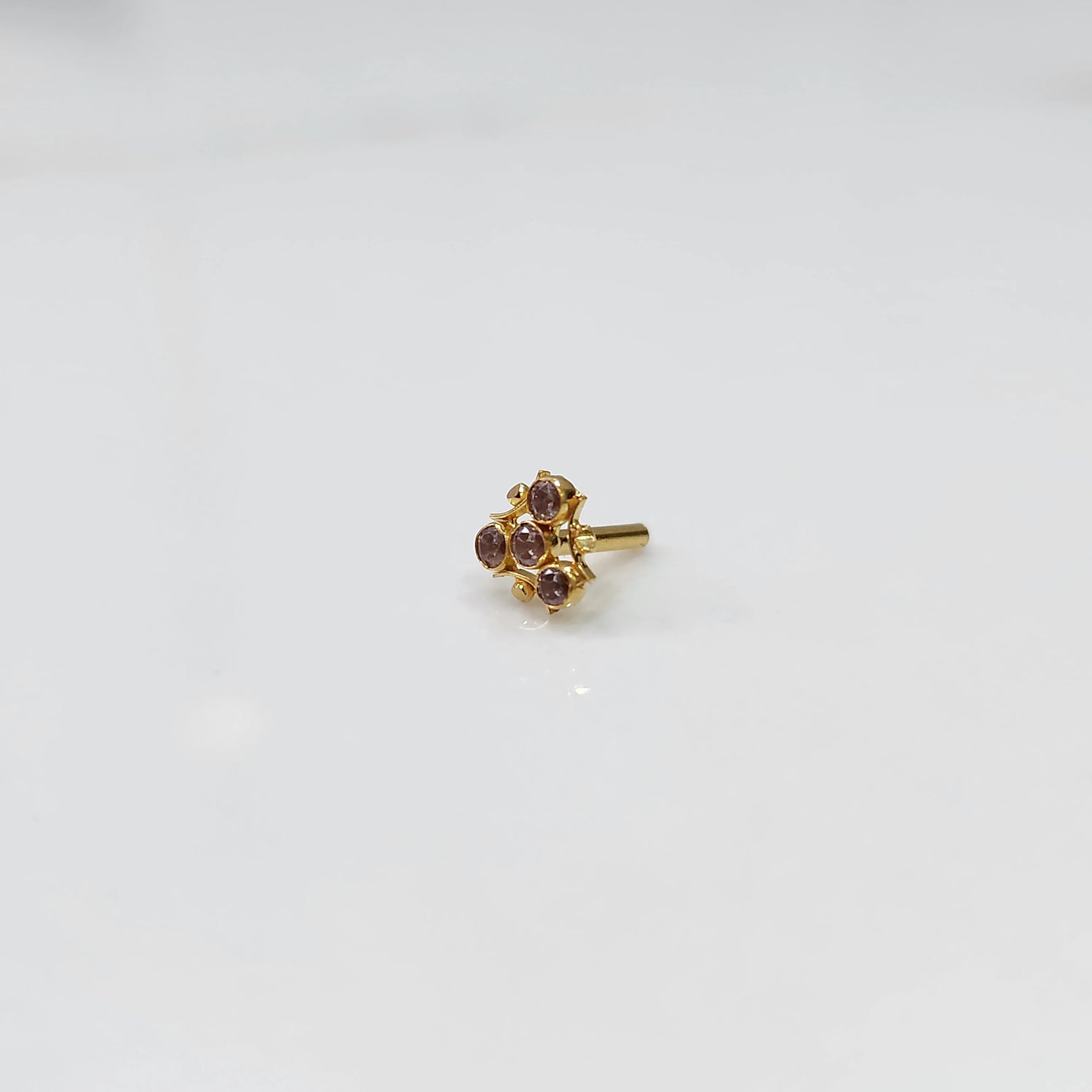 Tiny nose pin gold with delicate floral gemstone cluster on white background