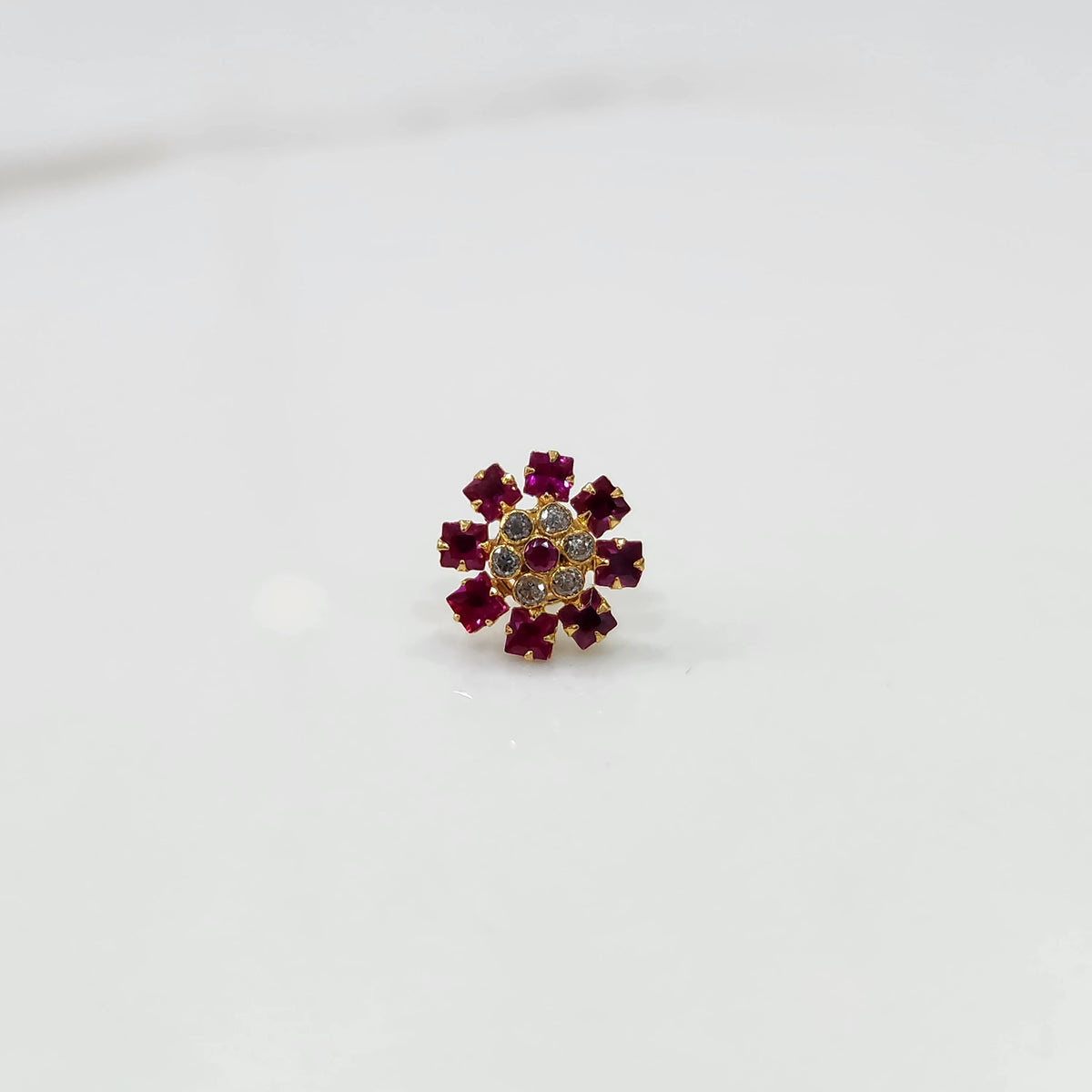 Gold nose pin design with red floral stone pattern on white background