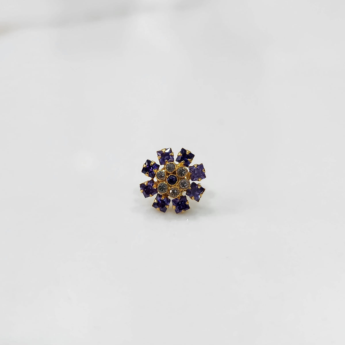 Gold nose pin design with blue floral stone pattern on white background