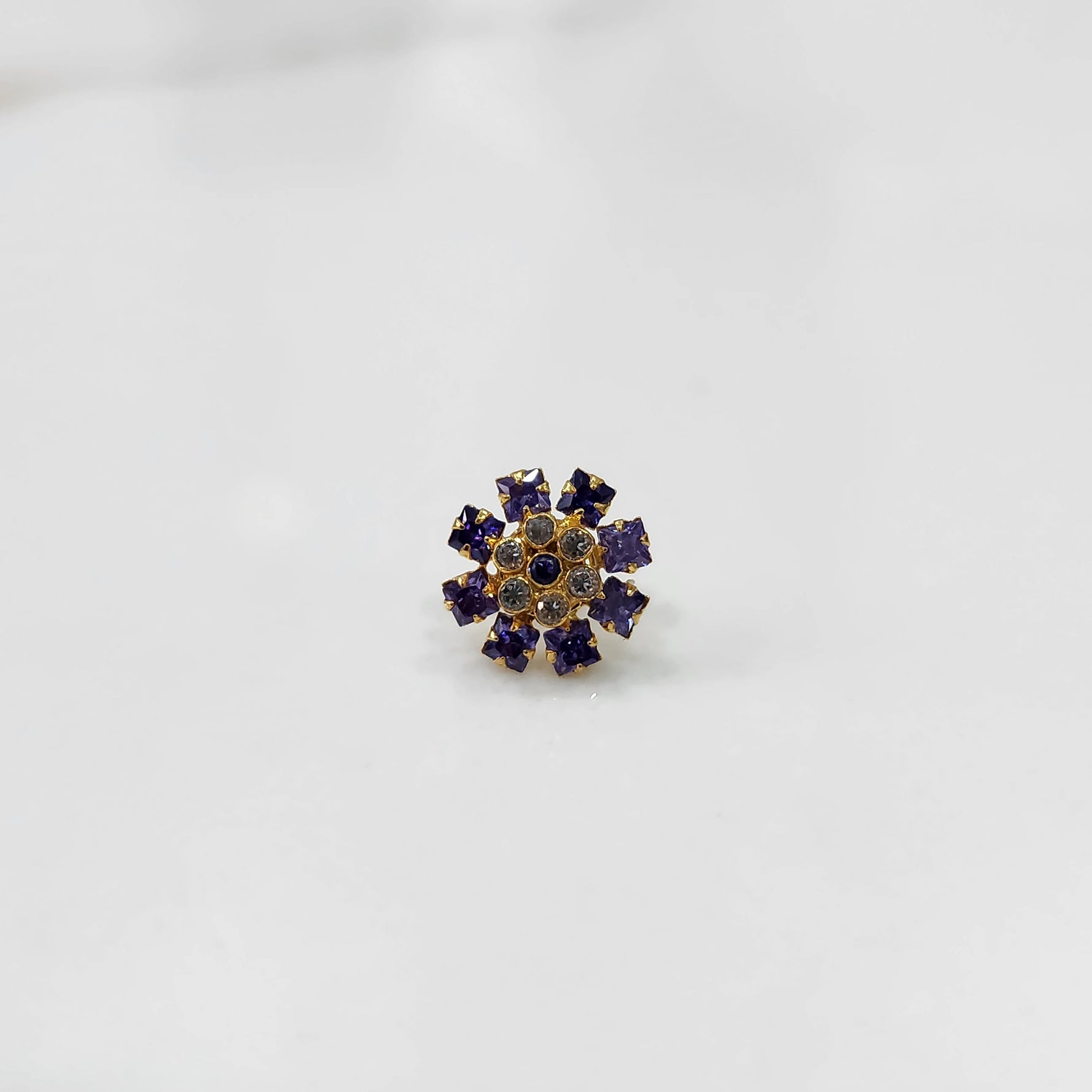 Gold nose pin design with blue floral stone pattern on white background