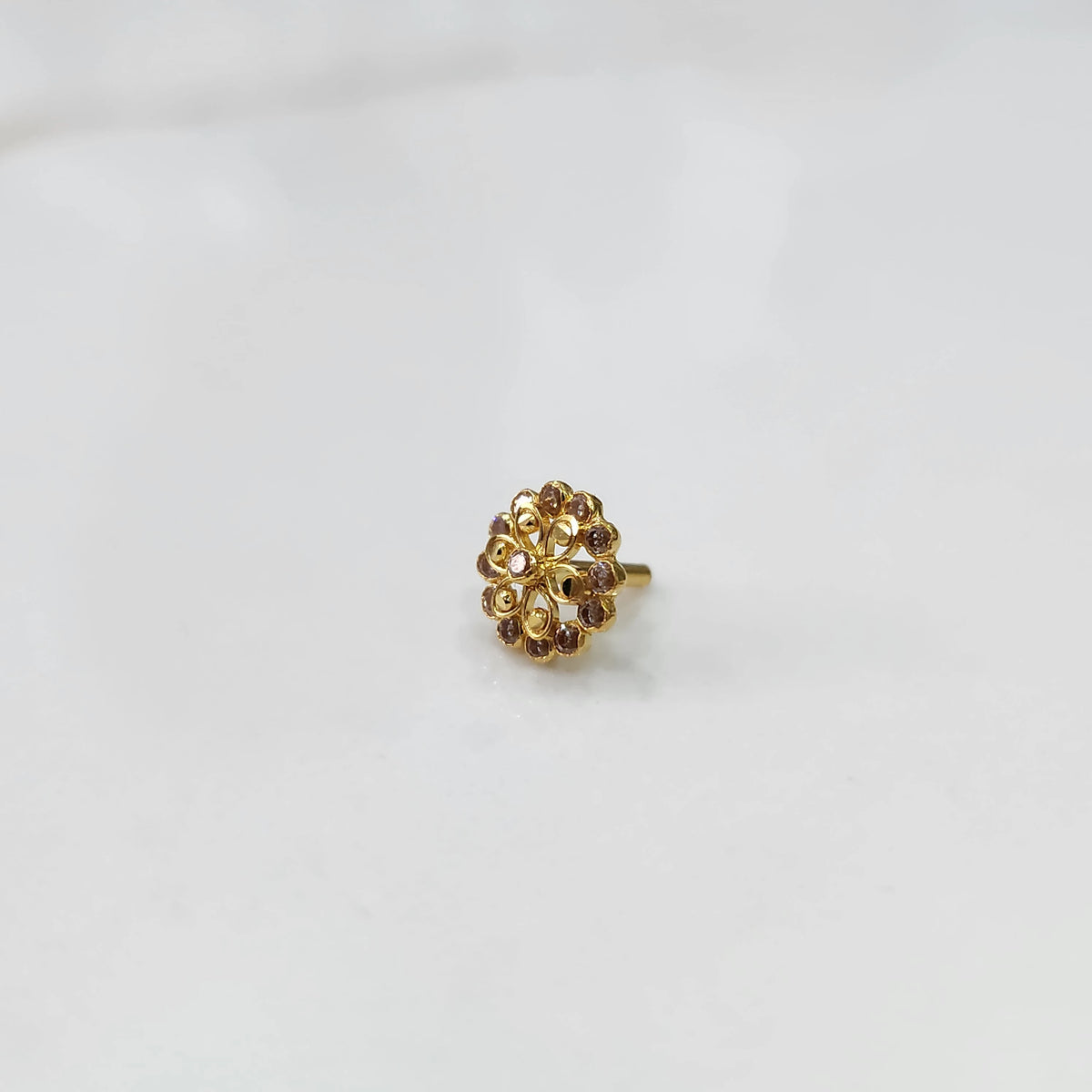 Side view gold nose pin design with white gemstone floral setting