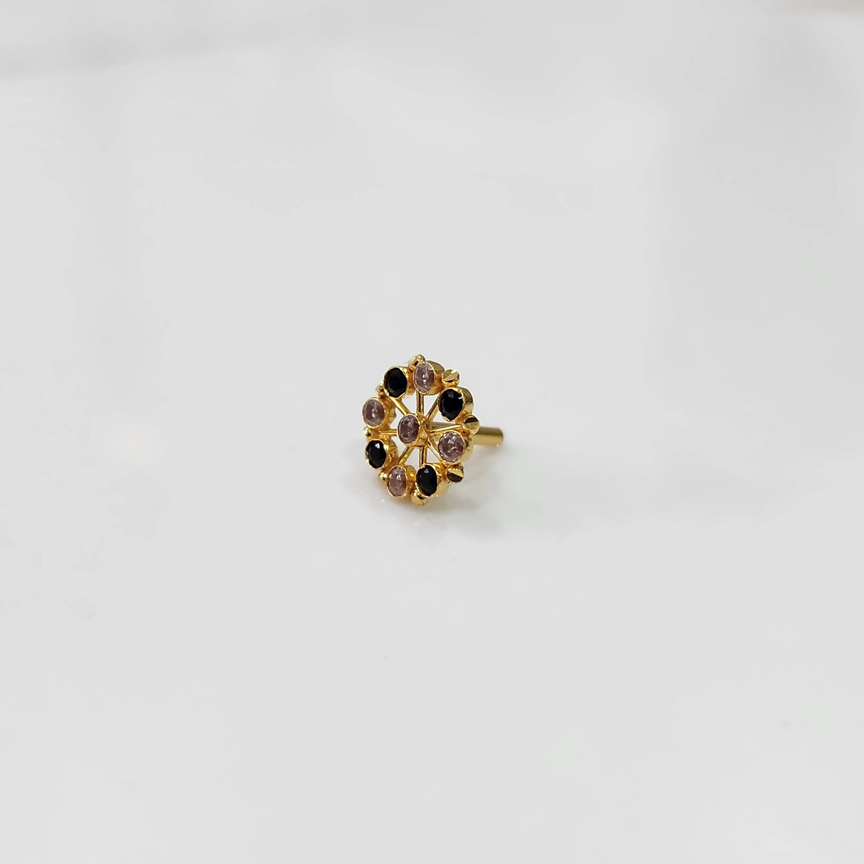 Gold pin nose with red and white floral stones on white background