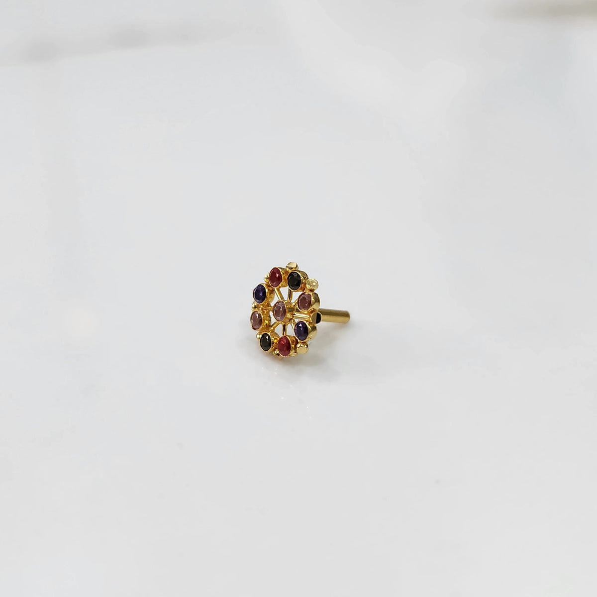 Gold pin nose with intricate multicolor floral setting on white background