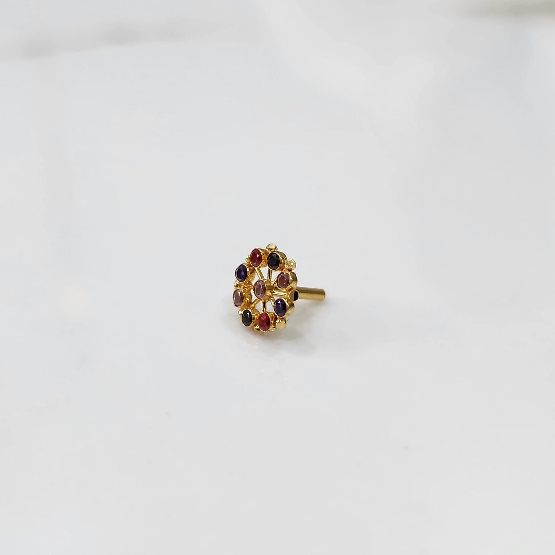 Gold pin nose with intricate multicolor floral setting on white background