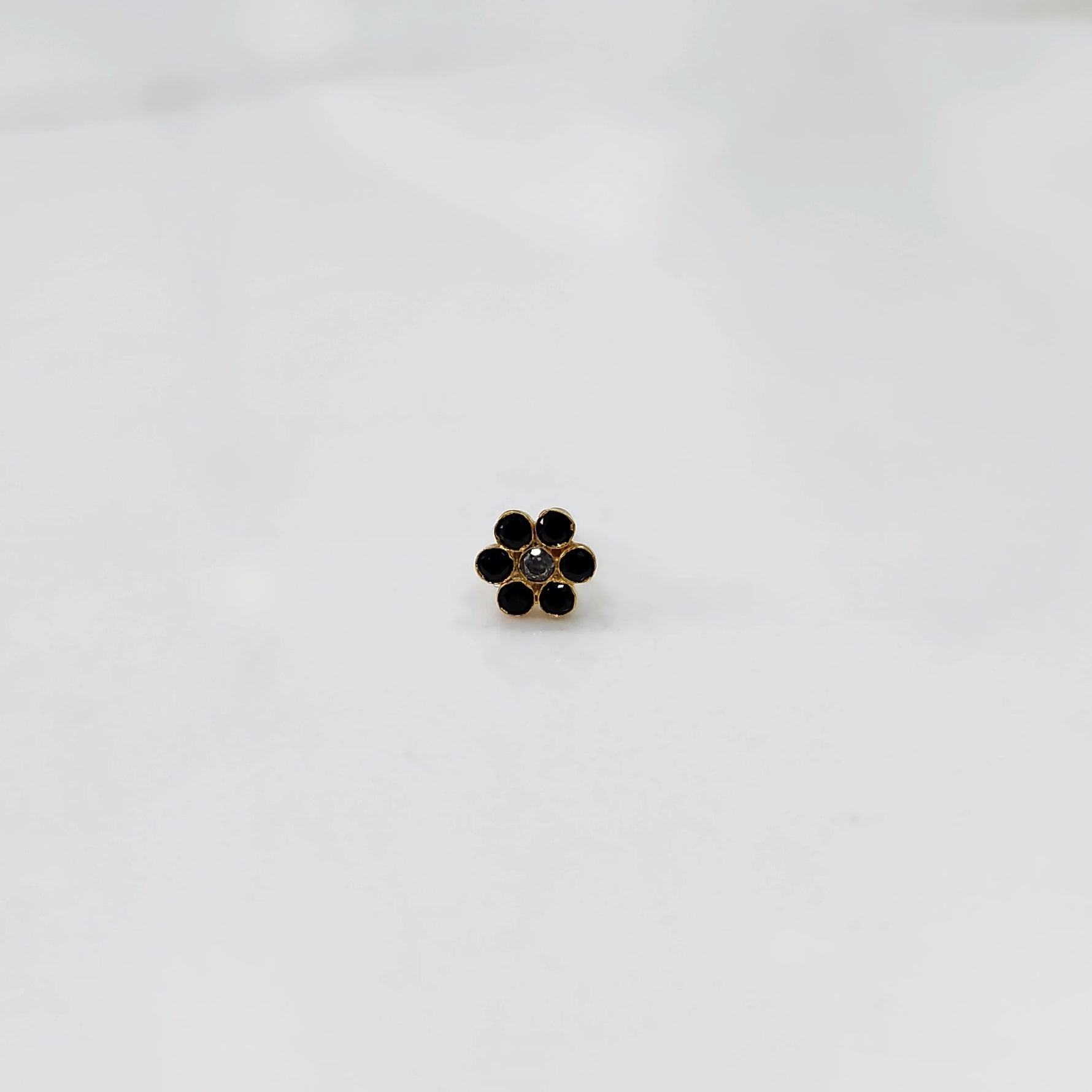 Close up nose pin design gold with dark stone floral cluster