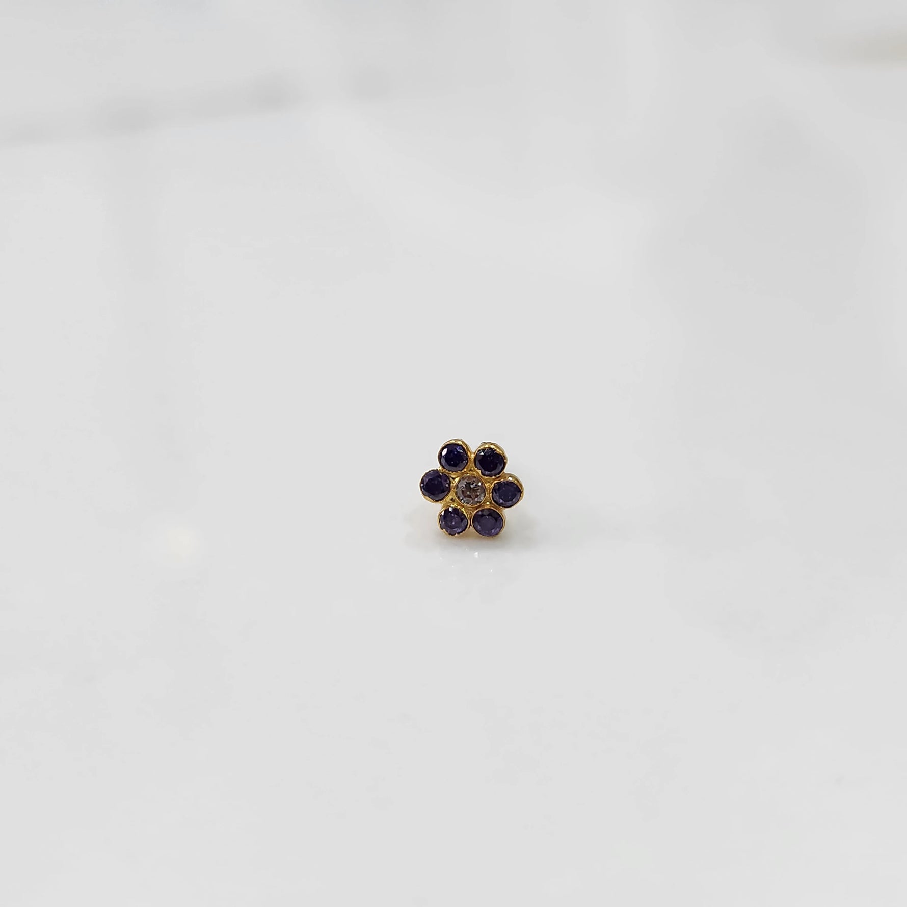 Nose pin design gold with blue stone floral cluster front view on white background