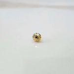 Close view of a tiny gold nose pin placed on a white surface highlighting its fine craftsmanship
