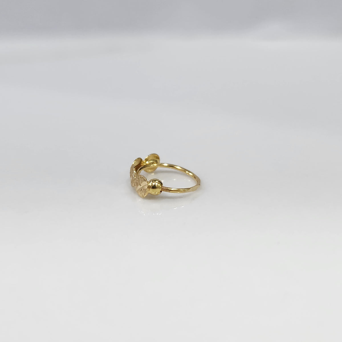 Crossbeam Circles gold nose ring in 18K gold displayed on a flat surface, featuring circular cross patterns with an elegant design