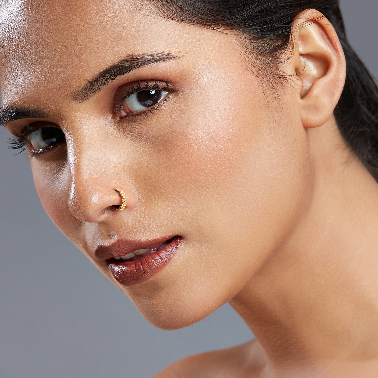 Model wearing Crossbeam Circles gold nose ring in 18K gold, showcasing elegant crosshatch texture and circular design
