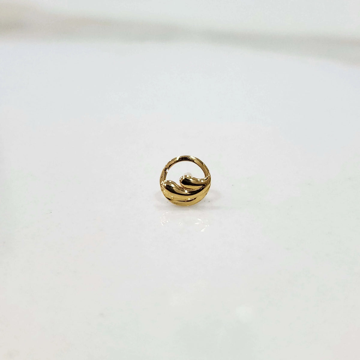 Close up of handcrafted circular gold nose pin design on white background elegant and refined for women