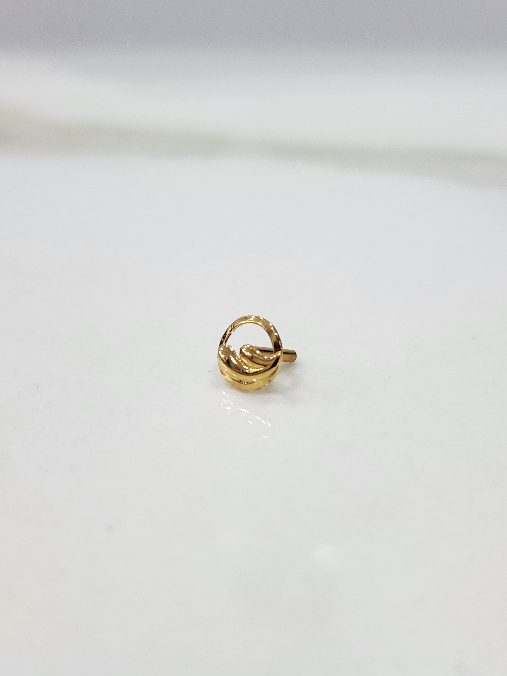 Encircled Waves gold nose pin in 18K gold displayed on a flat surface with elegant wave-inspired circular design