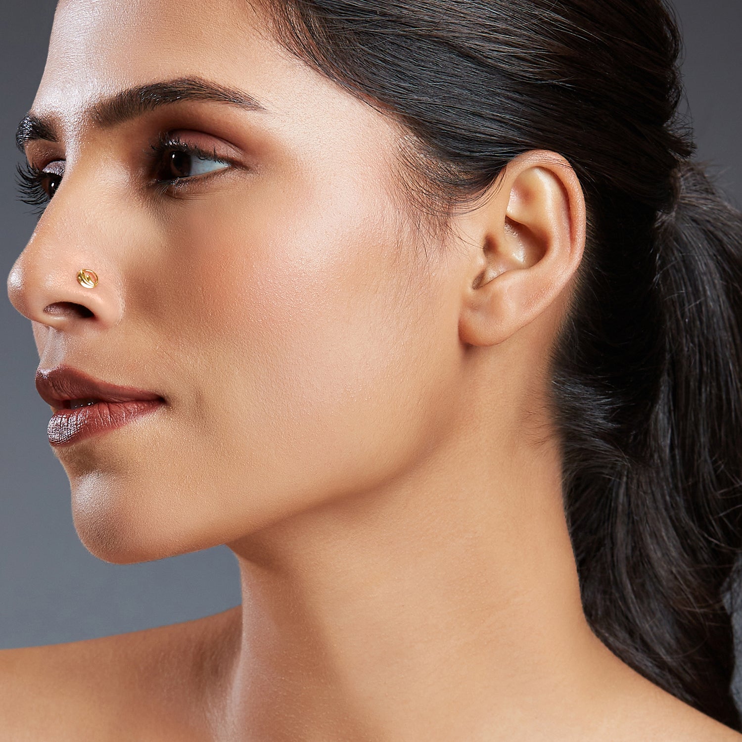 Model wearing Encircled Waves gold nose pin in 18K gold with artistic wave-inspired design symbolizing calmness and elegance