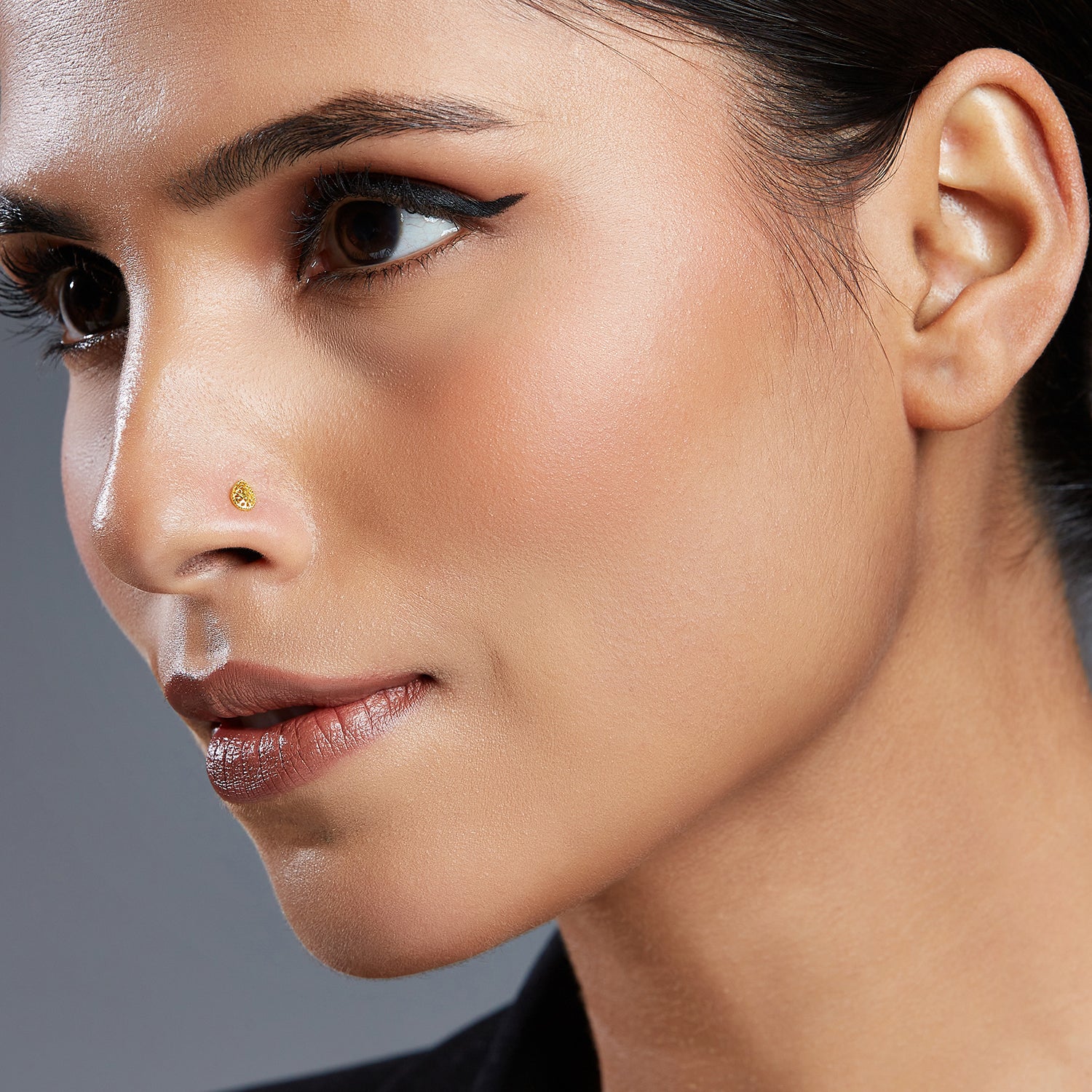 Model wearing Honeycomb Drop gold nose pin in teardrop design with hexagonal cutout pattern for a modern elegant look